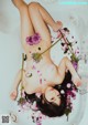 A naked woman laying in a bathtub filled with flowers.