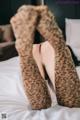 A woman in leopard print stockings laying on a bed.