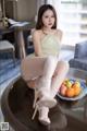 A woman sitting on top of a table next to a bowl of fruit.