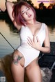 A woman in a white bodysuit posing on a dock.