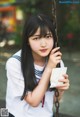 A young woman sitting on a swing holding a piece of paper.