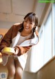 A woman in a bathrobe holding a bowl of food.