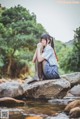 A woman sitting on a rock in the middle of a river.