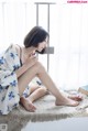 A woman sitting on a window sill with her legs crossed.