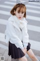 A young girl wearing a white coat and a black skirt.