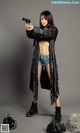 A woman in a black jacket holding a gun.