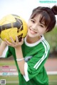 A young woman holding a soccer ball on a field.