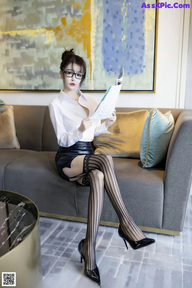 A woman sitting on a couch reading a book.
