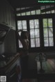 A naked woman standing in a kitchen next to a window.