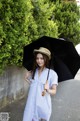 A woman in a blue and white striped shirt dress holding an umbrella.