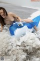 A naked woman riding an inflatable whale in the ocean.