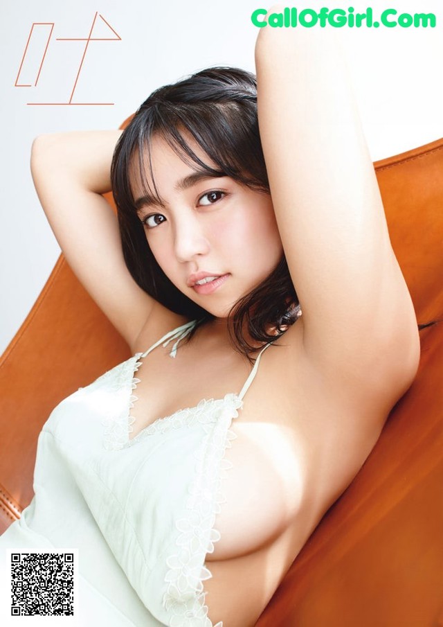 A woman in a white dress sitting on a brown chair.