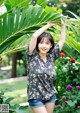 A woman in shorts and a floral shirt posing for a picture.